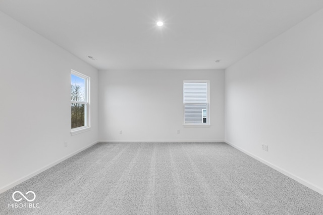 spare room with carpet flooring, visible vents, and baseboards