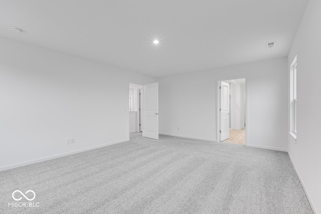 empty room featuring recessed lighting, baseboards, and light colored carpet