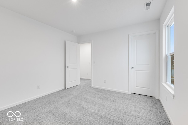 unfurnished bedroom featuring light carpet, visible vents, and baseboards