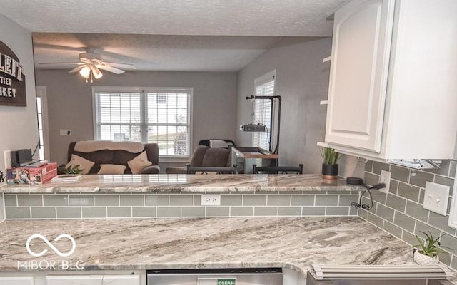 kitchen with decorative backsplash, white cabinetry, ceiling fan, and a textured ceiling