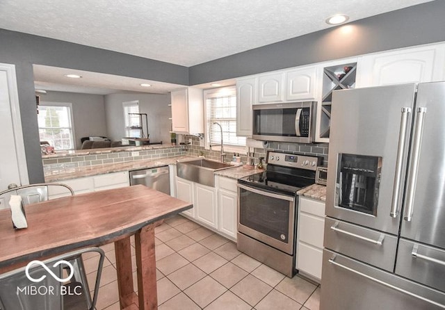 kitchen featuring appliances with stainless steel finishes, a textured ceiling, sink, white cabinets, and light tile patterned flooring