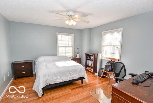 bedroom with multiple windows, a textured ceiling, light hardwood / wood-style floors, and ceiling fan