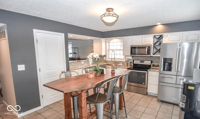 kitchen with sink, white cabinetry, stainless steel appliances, and light tile patterned floors