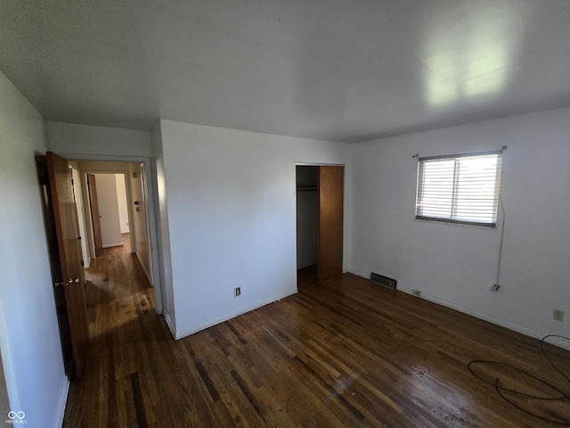 unfurnished bedroom with dark wood-type flooring and a closet