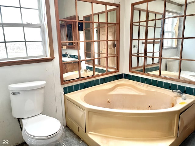 bathroom featuring toilet, tile patterned floors, and a bath