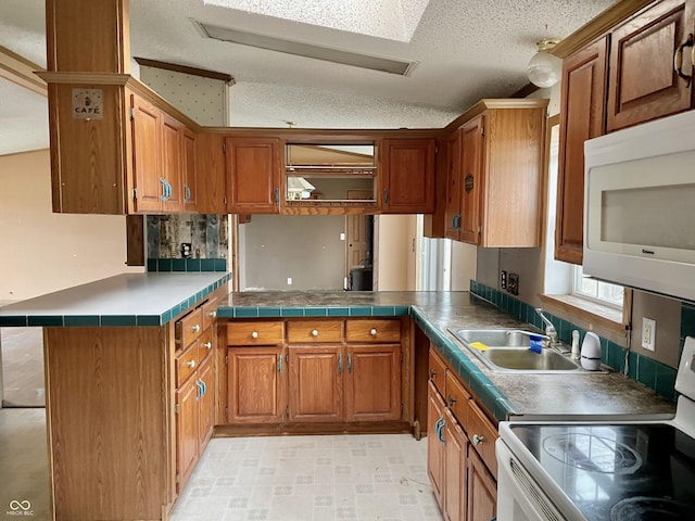 kitchen featuring sink, white appliances, a textured ceiling, and kitchen peninsula