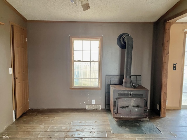 interior space with ceiling fan, hardwood / wood-style floors, a textured ceiling, and a wood stove