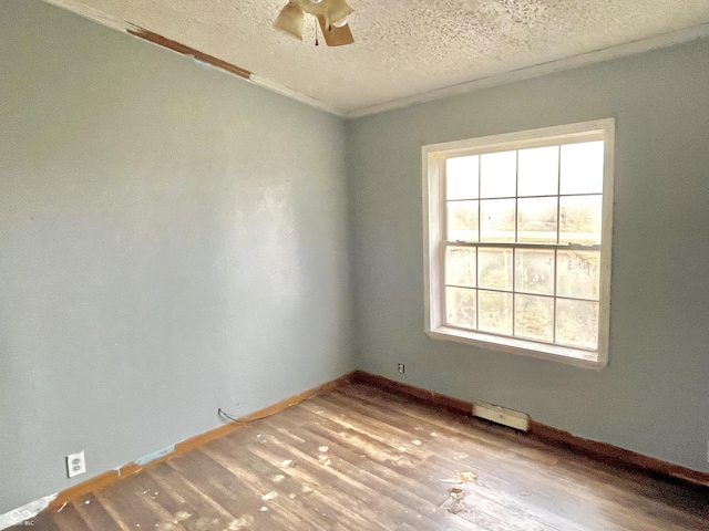 spare room with a textured ceiling, light wood-type flooring, ceiling fan, and ornamental molding