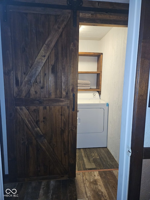 clothes washing area with dark hardwood / wood-style floors, a barn door, and washer / dryer