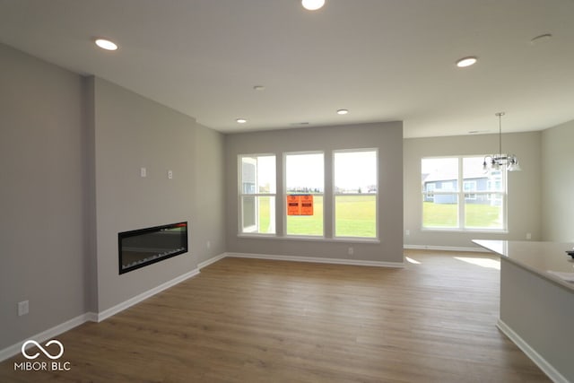 unfurnished living room featuring light wood-type flooring and a chandelier