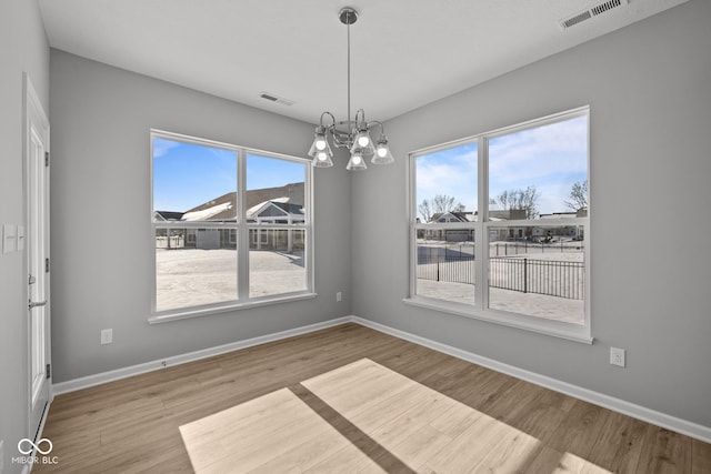 unfurnished dining area with light hardwood / wood-style flooring and a chandelier