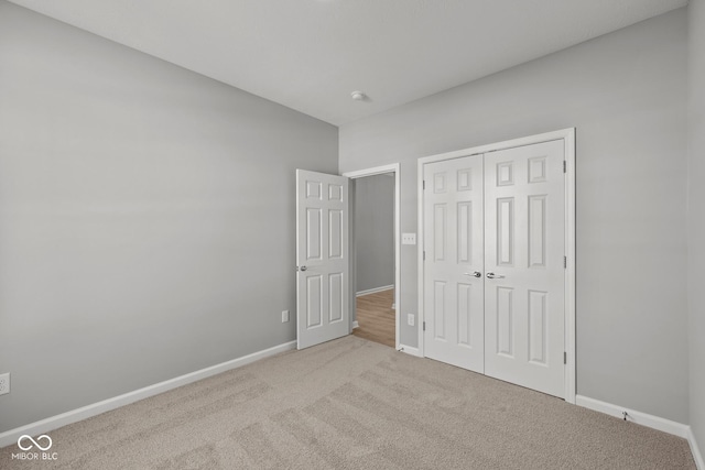 unfurnished bedroom featuring a closet and light colored carpet