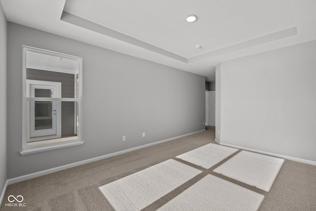 carpeted spare room featuring a raised ceiling