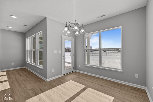 unfurnished dining area with hardwood / wood-style flooring and a notable chandelier