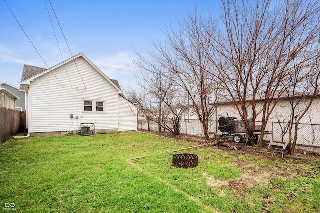 rear view of property with a lawn and an outdoor fire pit