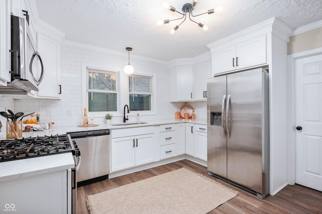 kitchen with pendant lighting, dark wood-type flooring, sink, appliances with stainless steel finishes, and white cabinetry