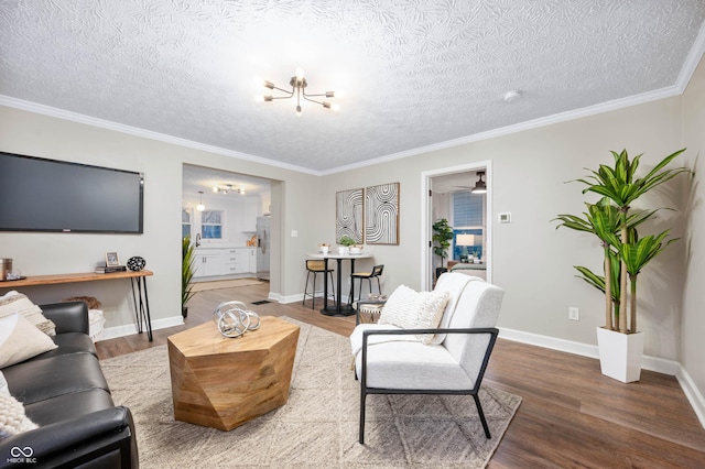 living room with a textured ceiling, an inviting chandelier, crown molding, and hardwood / wood-style floors