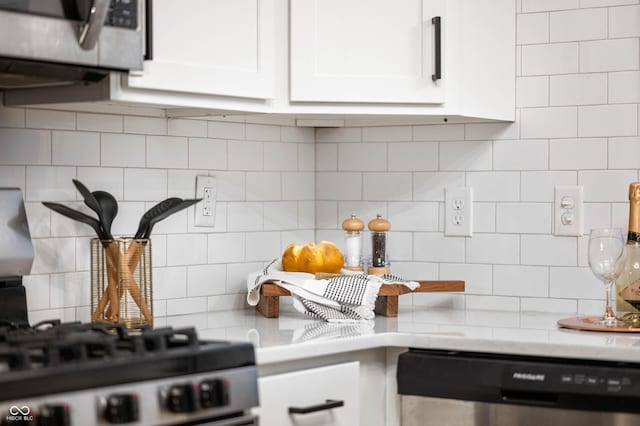 kitchen featuring dishwasher, backsplash, range with gas cooktop, and white cabinetry