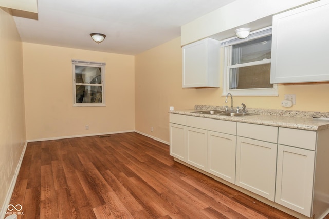 kitchen with hardwood / wood-style flooring, white cabinets, and sink