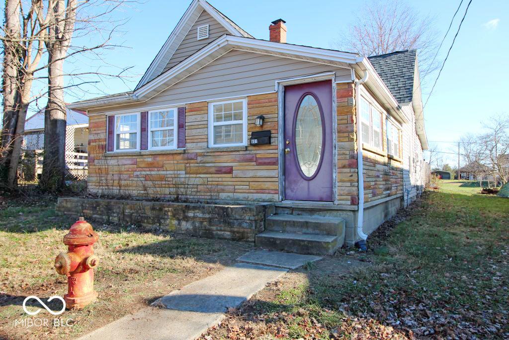 view of front of property with entry steps, a shingled roof, a chimney, and a front lawn