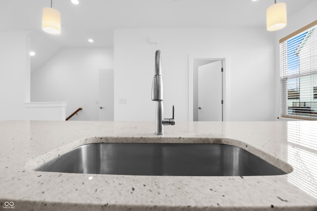 interior details featuring light stone countertops, sink, and pendant lighting