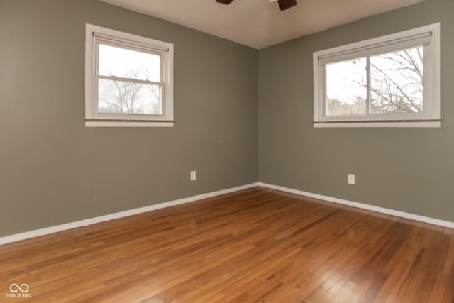 empty room with hardwood / wood-style floors, ceiling fan, and a healthy amount of sunlight