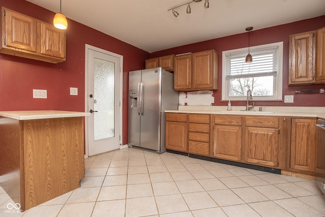 kitchen featuring kitchen peninsula, stainless steel fridge, rail lighting, sink, and hanging light fixtures