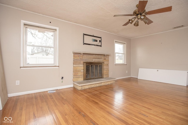 unfurnished living room with ceiling fan, ornamental molding, a textured ceiling, and light hardwood / wood-style flooring