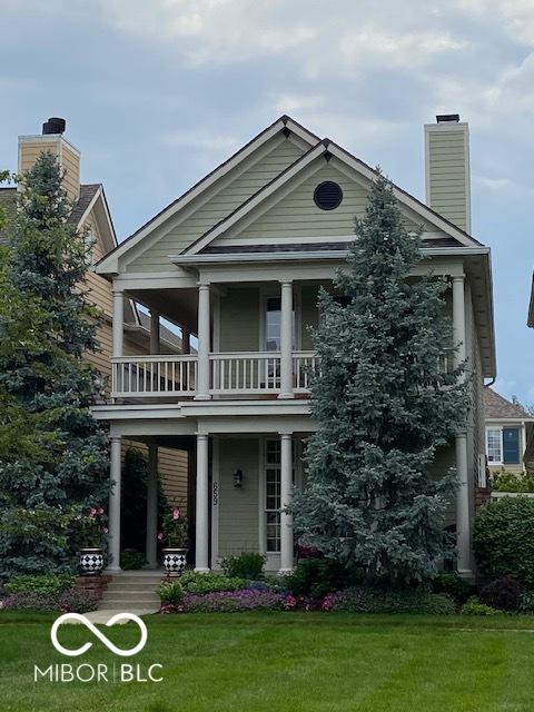 greek revival house featuring a porch, a front yard, and a balcony