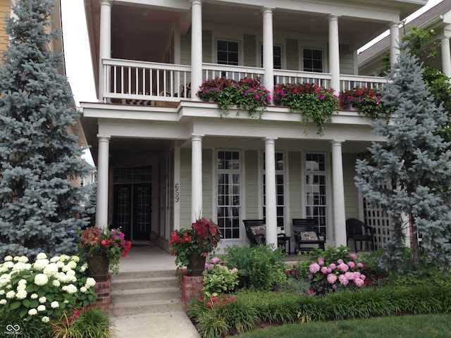 view of exterior entry featuring a porch and a balcony