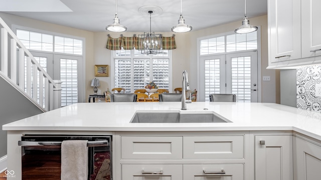 kitchen with sink, white cabinets, beverage cooler, and decorative light fixtures