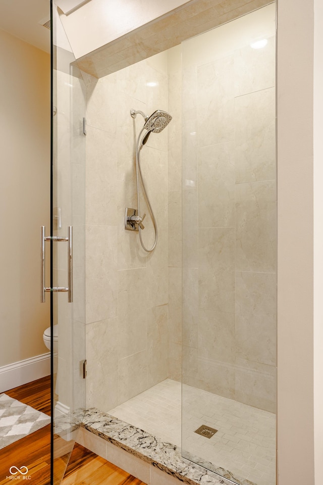 bathroom featuring toilet, walk in shower, and hardwood / wood-style flooring