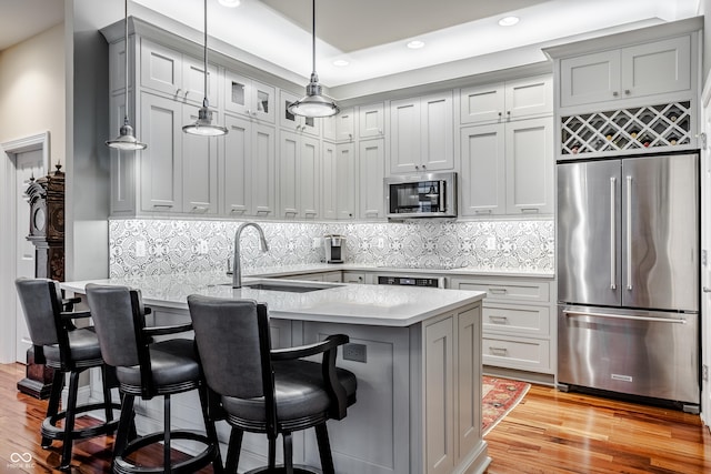 kitchen with light wood-type flooring, appliances with stainless steel finishes, a breakfast bar area, and sink