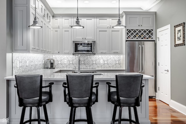 kitchen featuring appliances with stainless steel finishes, a kitchen breakfast bar, light stone countertops, and kitchen peninsula