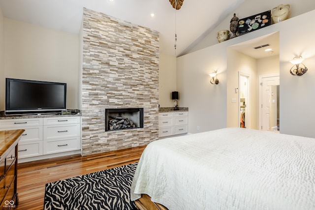 bedroom featuring light hardwood / wood-style flooring, high vaulted ceiling, and a fireplace