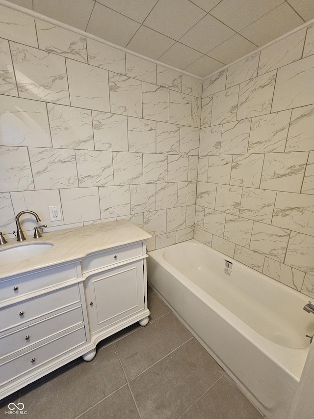 bathroom with vanity, a tub to relax in, tile patterned floors, and tile walls