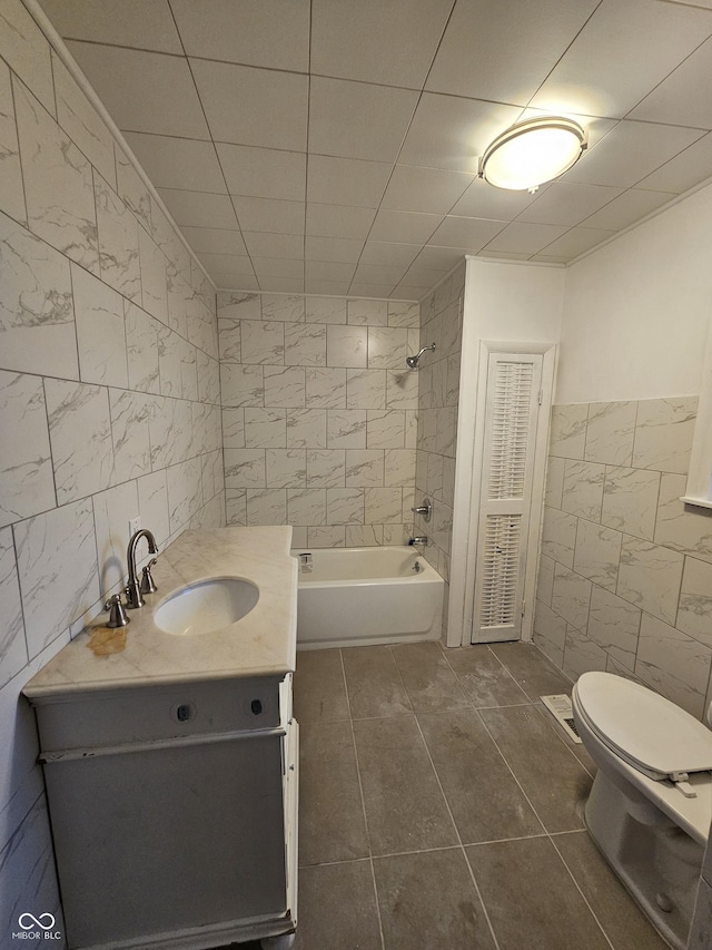 full bathroom featuring vanity, toilet, tile walls, and tiled shower / bath