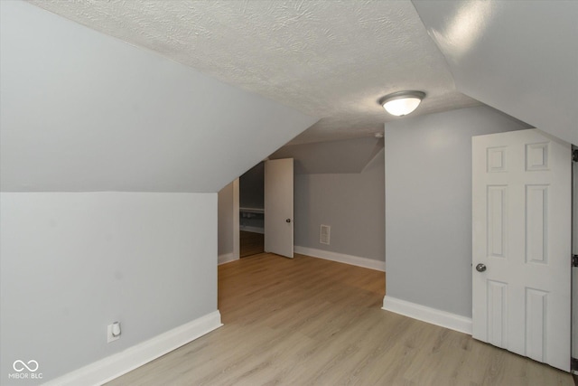 bonus room featuring light hardwood / wood-style floors, a textured ceiling, and vaulted ceiling