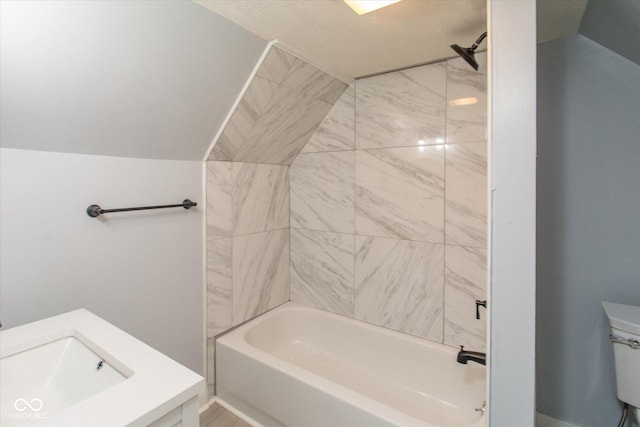 full bathroom with sink, tiled shower / bath, vaulted ceiling, and toilet