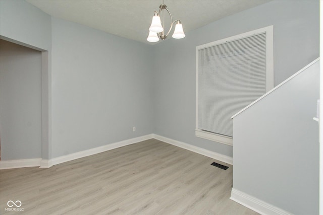 unfurnished dining area with light wood-type flooring and an inviting chandelier