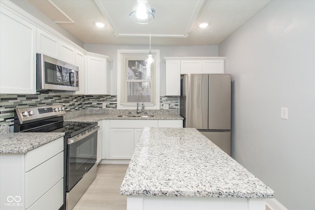 kitchen with backsplash, sink, hanging light fixtures, white cabinetry, and stainless steel appliances