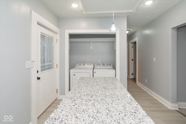 clothes washing area featuring light hardwood / wood-style flooring and washing machine and clothes dryer