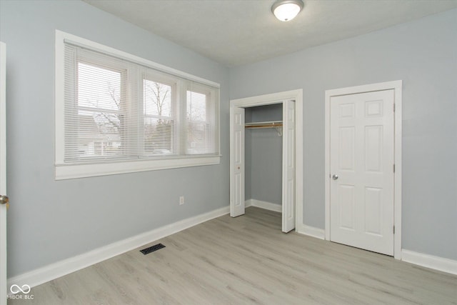 unfurnished bedroom with a closet and light hardwood / wood-style floors