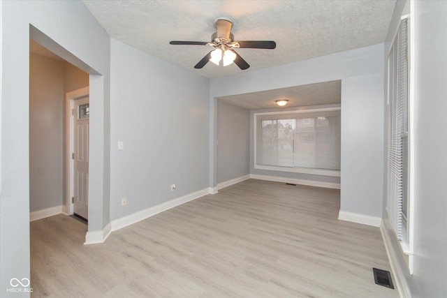 empty room with ceiling fan, a textured ceiling, and light hardwood / wood-style flooring