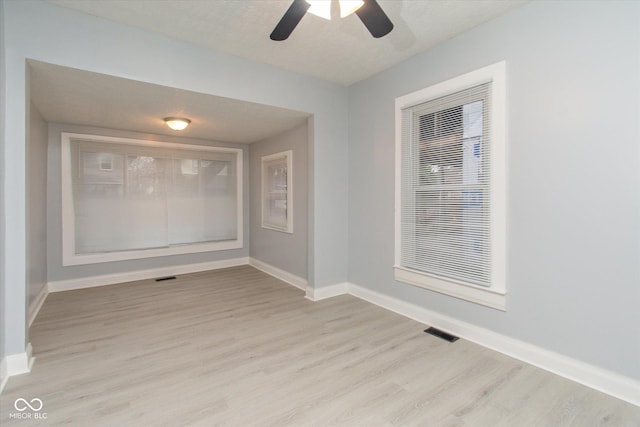 unfurnished room with a textured ceiling, light hardwood / wood-style floors, and ceiling fan