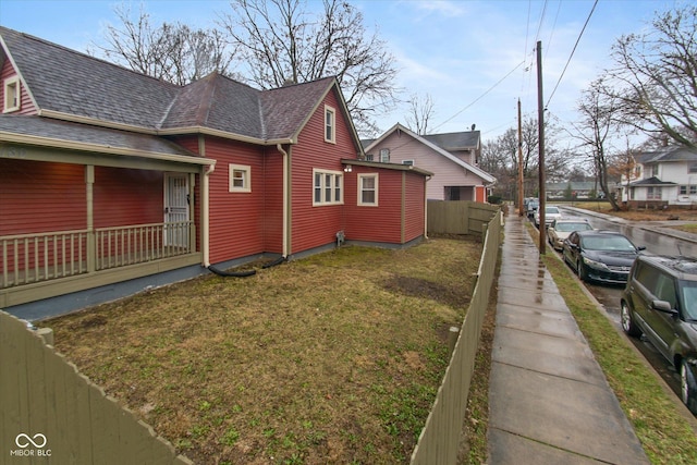 view of side of home with covered porch and a yard