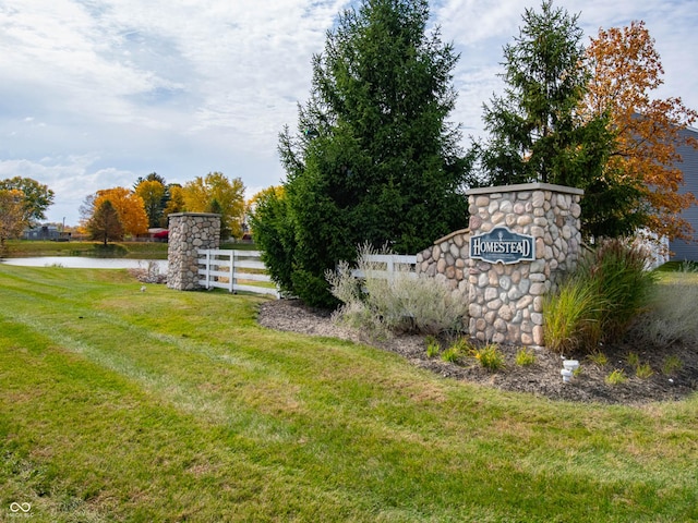 community / neighborhood sign with a lawn and a water view