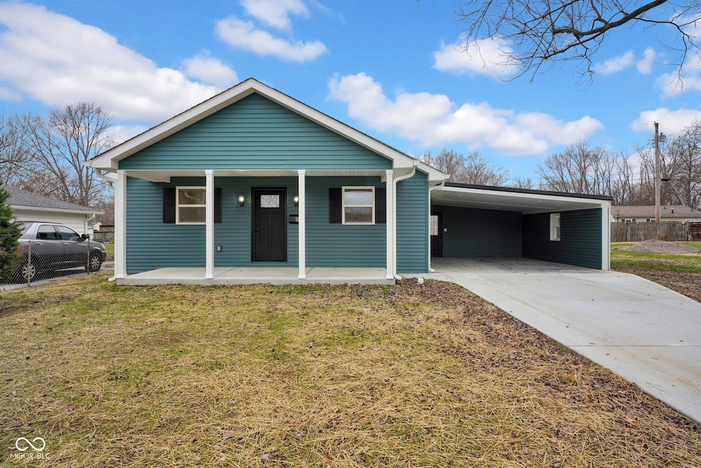 view of front of house with a front lawn, covered porch, and a carport