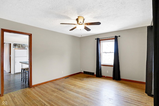 spare room with ceiling fan, light hardwood / wood-style flooring, and a textured ceiling