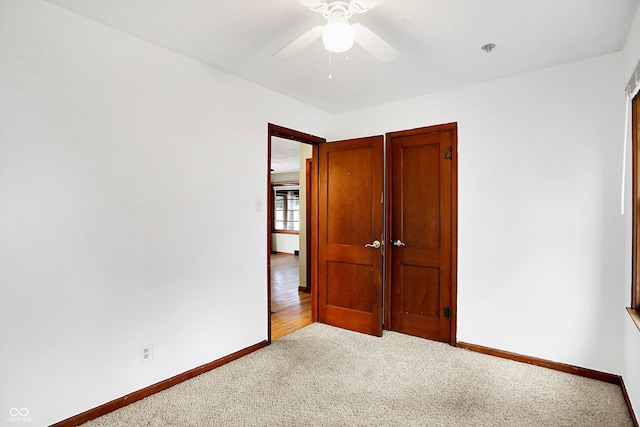 unfurnished bedroom featuring light carpet, a closet, and ceiling fan